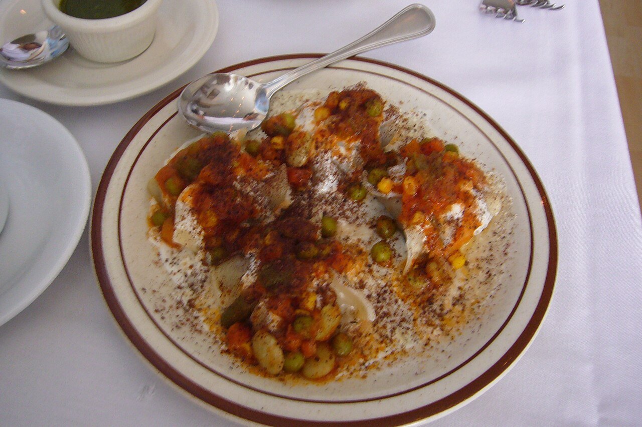 Representative photograph of Afghan Mantu. The photograph includes peas and a red sauce; this recipe uses a yellow split-pea topping.