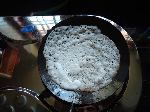 Representative photograph of Appam Hoppers. The photograph shows a Kerala appam cooking in a pan; this recipe follows a Sri Lankan-style hopper batter.