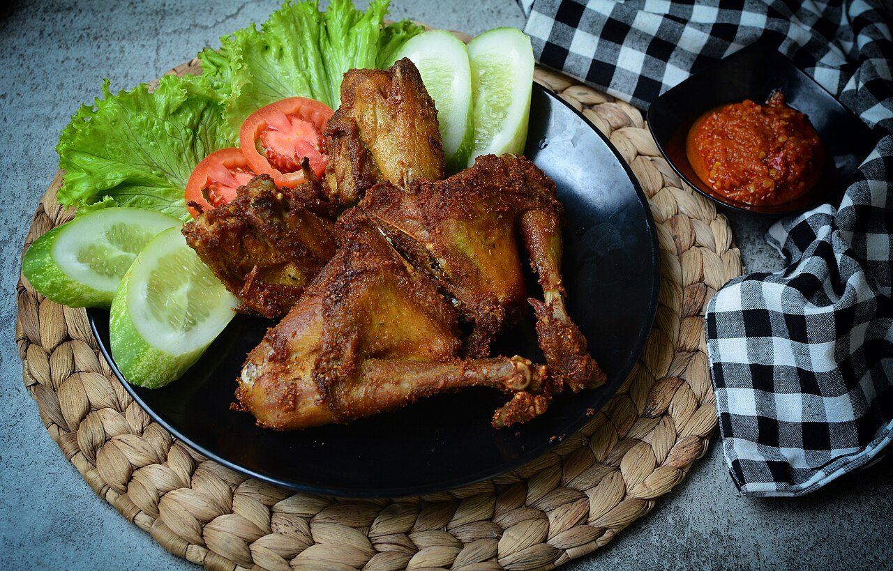 Representative photograph of Ayam Goreng. The photograph shows ayam goreng Kalasan with salad and sambal; this recipe uses a simpler spice mixture.