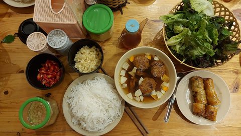 Representative photograph of Bun Cha. The photograph includes spring rolls and extra herbs not included in this recipe.