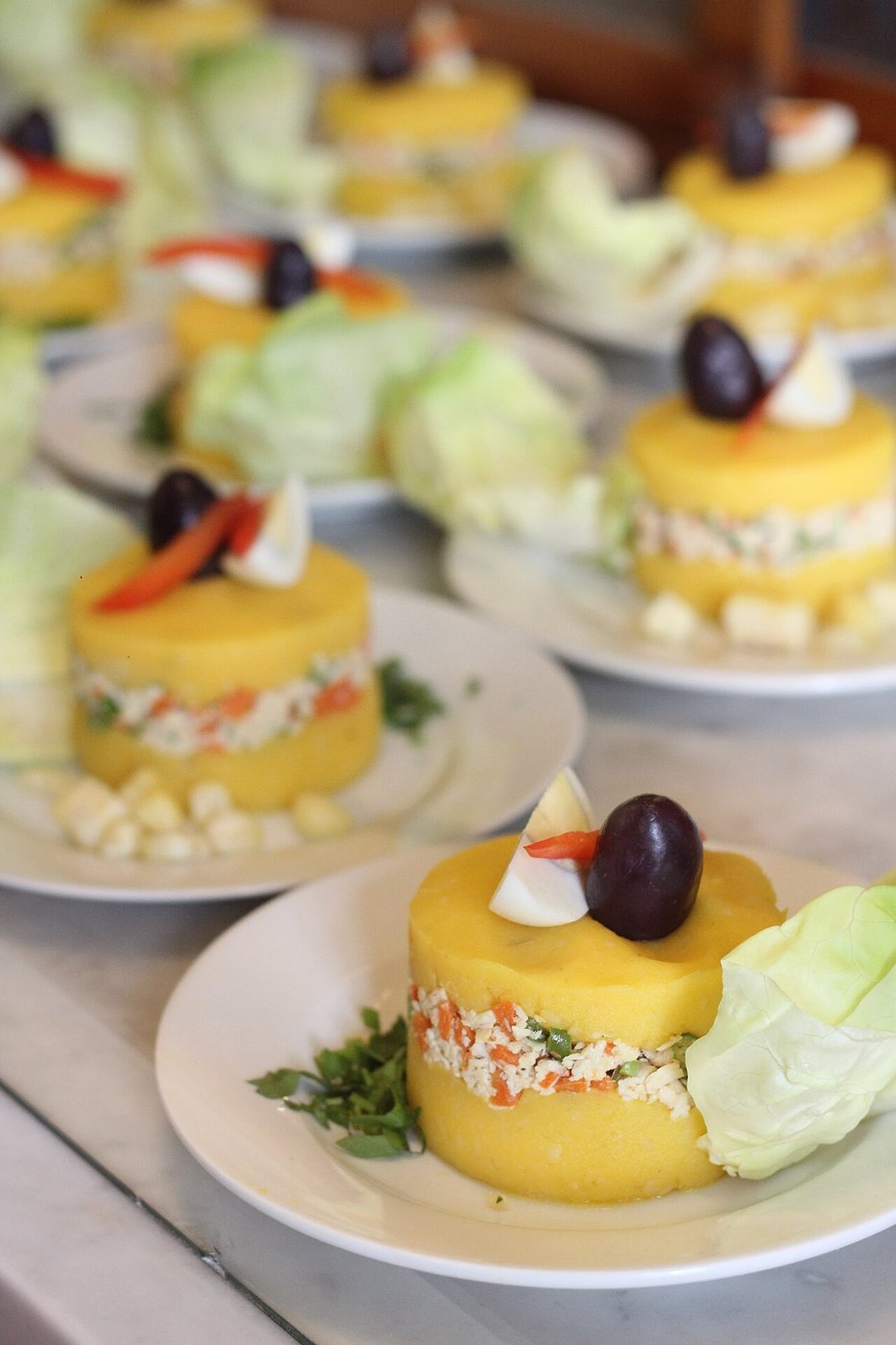 Representative photograph of Causa Limena. The photograph shows individual portions with olives and extra garnish; this recipe sets causa in one dish.