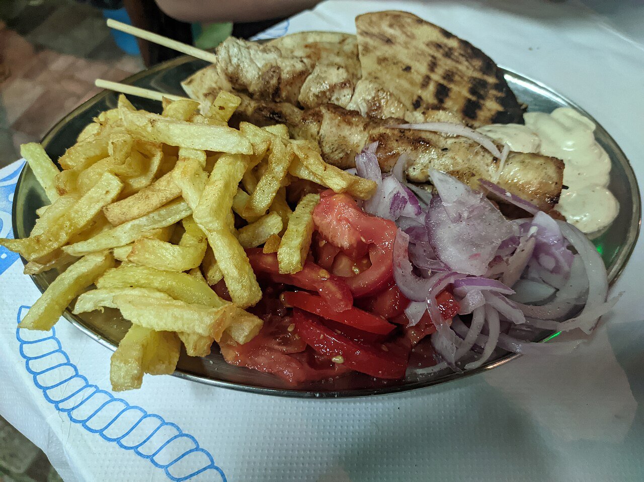 Representative photograph of Chicken Souvlaki. The photograph includes chips, bread, salad and sauce not included in this recipe.