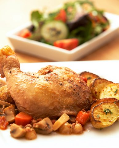 Representative photograph of Coq au Vin. The photograph includes side vegetables and a different-looking wine sauce; this recipe uses red wine.