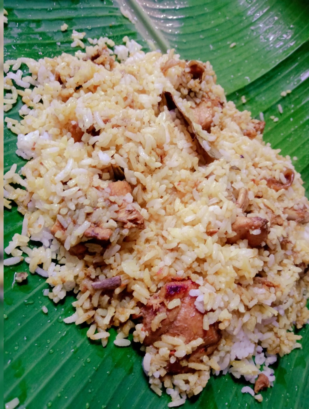Chicken biryani served on a green banana leaf