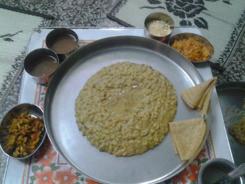 Khichdi in the center of a steel thali with bread and side dishes