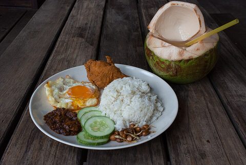 Representative photograph of Nasi Lemak. The photo includes fried chicken and a coconut drink as accompaniments.