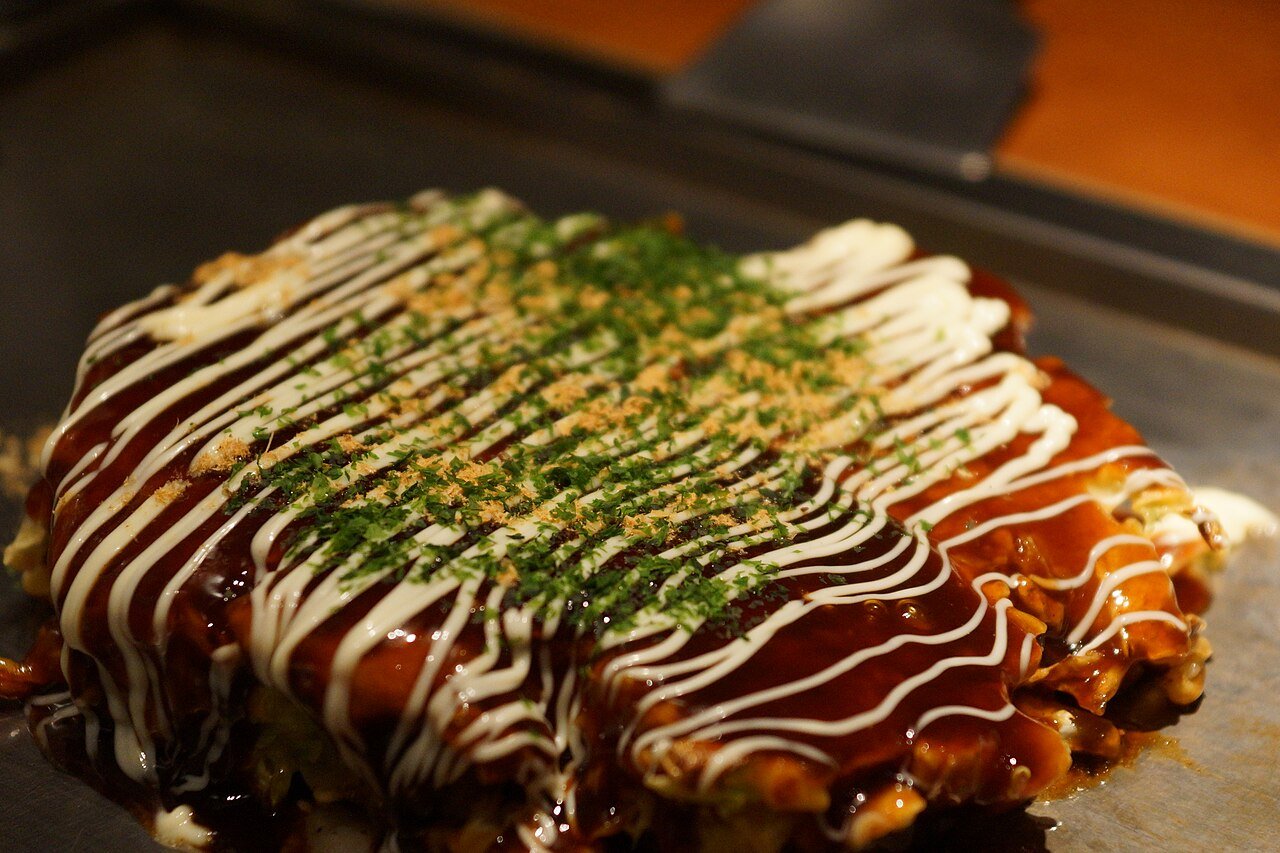Representative photograph of Okonomiyaki. The photograph includes extra green garnish not included in the recipe.