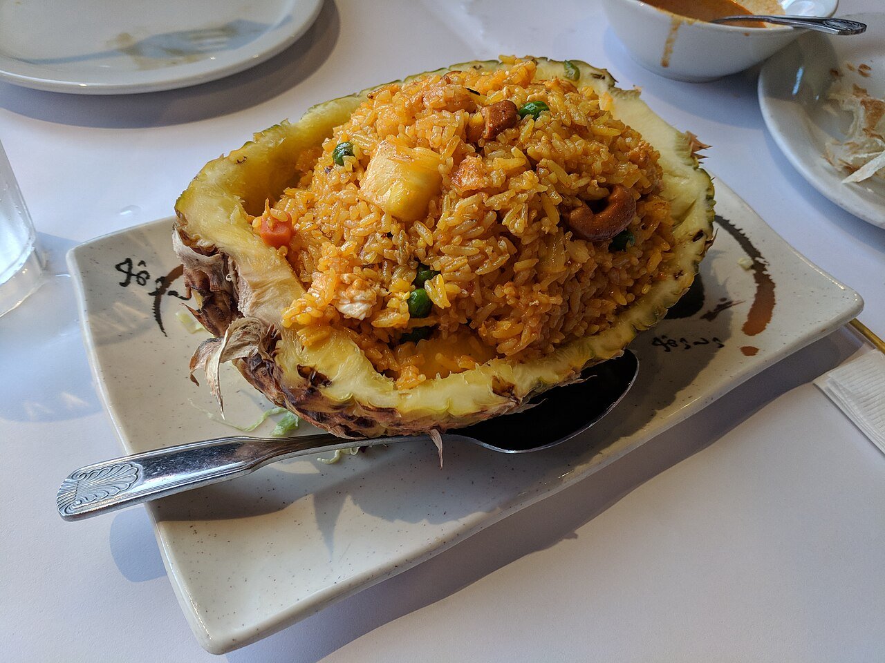 Representative photograph of Pineapple Fried Rice. The photo serves rice in a pineapple shell; this recipe uses pineapple chunks without a shell serving bowl.