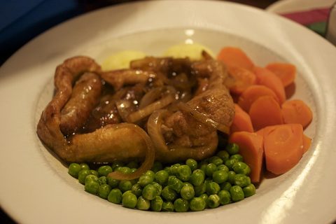 Representative photograph of Toad in the Hole. The photograph includes gravy, peas and carrots not included in this recipe.